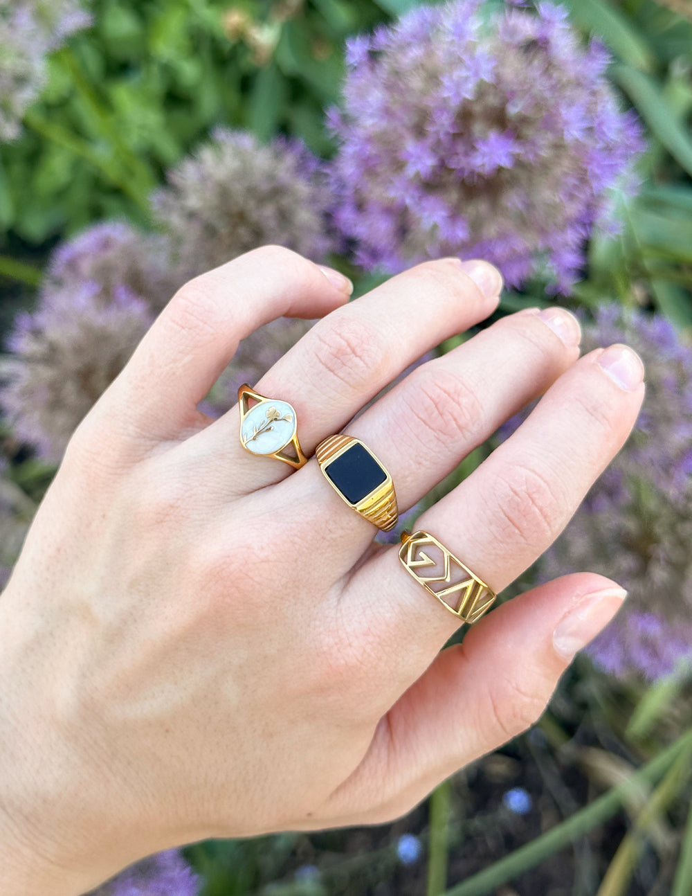 Hand wearing two gold rings with floral background