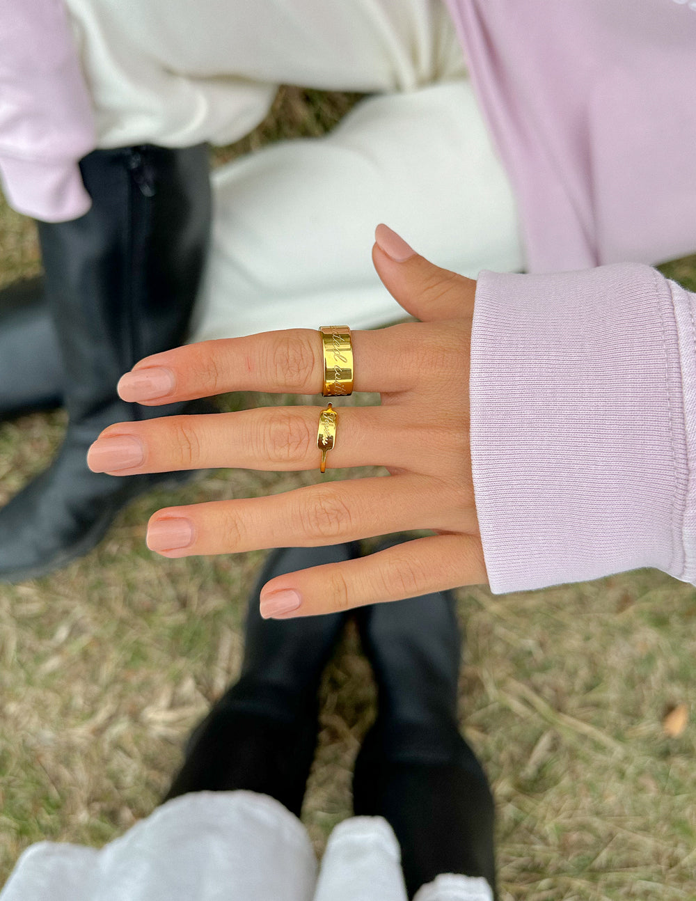 Hand wearing a gold ring with a blurred background