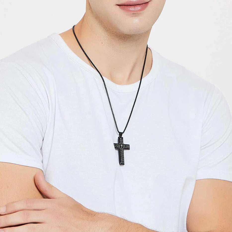 Person wearing a black cross necklace on a plain background