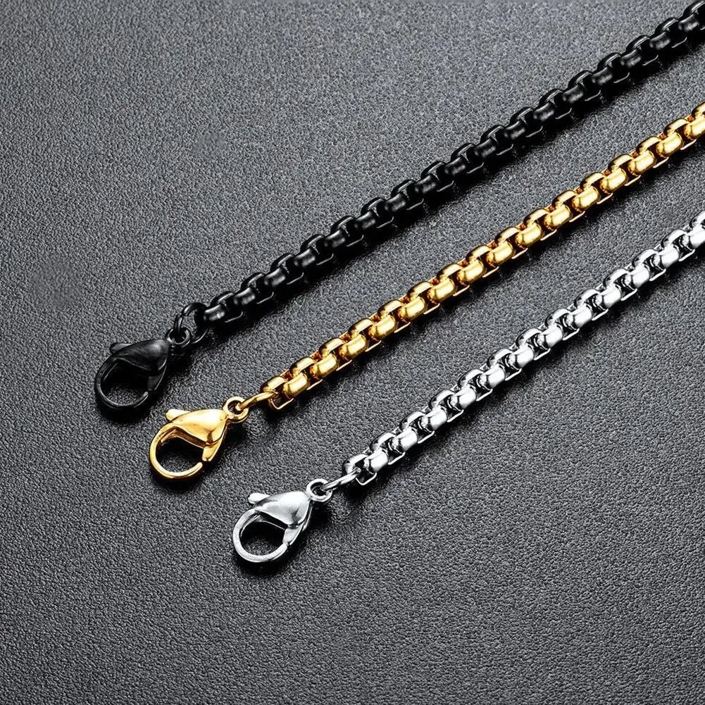Three chain necklaces in black, gold, and silver on a gray background