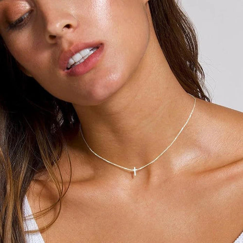 Close-up of a woman wearing a delicate necklace against a neutral background