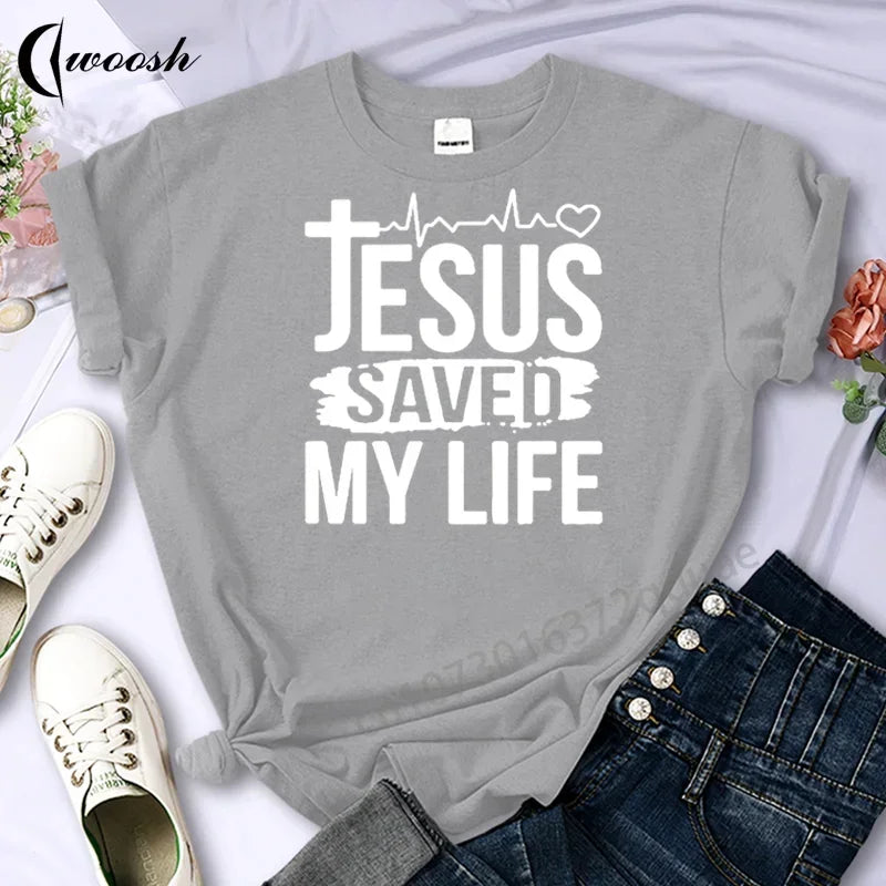 Gray t-shirt with 'Jesus Saved My Life' text on a white background with shoes and jeans.