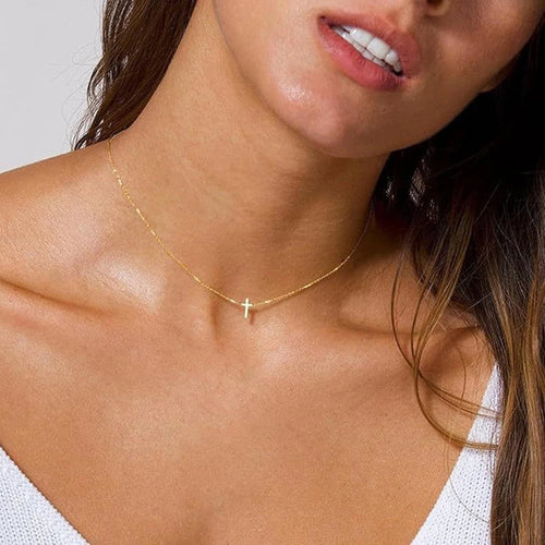 Close-up of a woman wearing a gold necklace with a cross pendant.