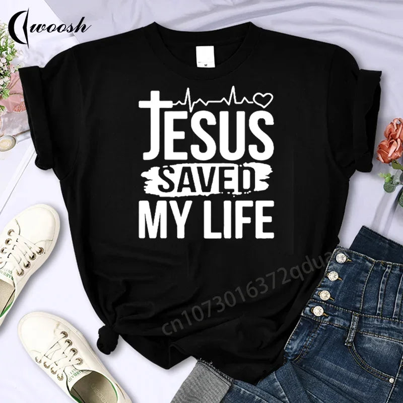 Black t-shirt with 'Jesus Saved My Life' text on a white background with shoes and jeans.