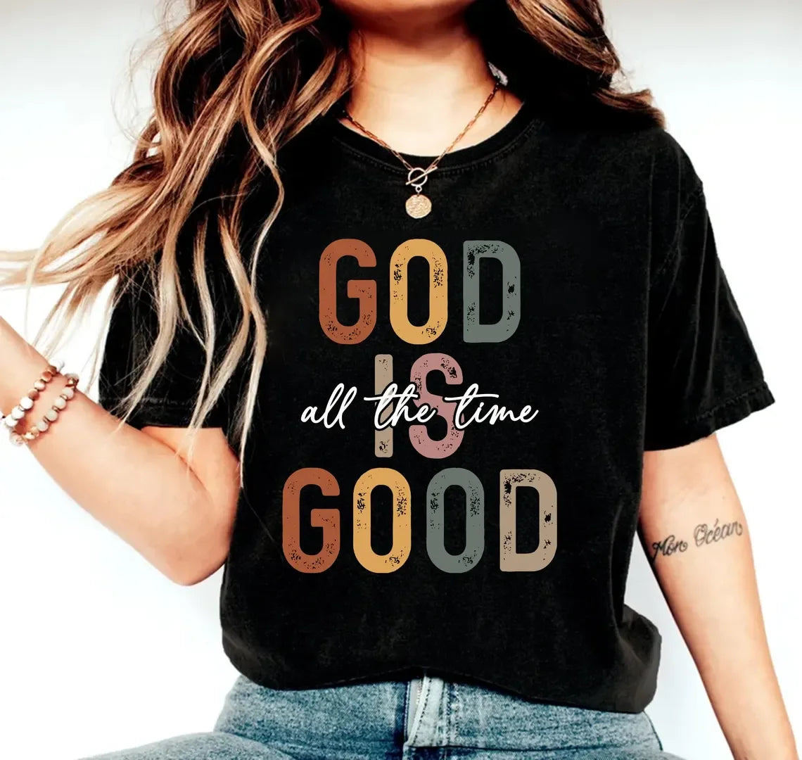 Person wearing a black t-shirt with 'GOD IS all the time GOOD' text design.