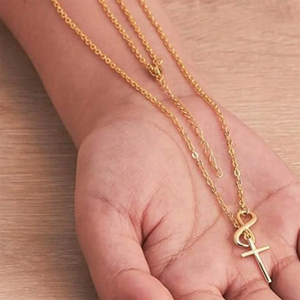 Gold necklace with a cross pendant on a hand against a wooden background