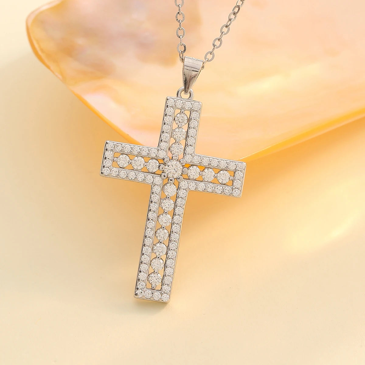 Silver cross pendant with clear stones on a yellow background