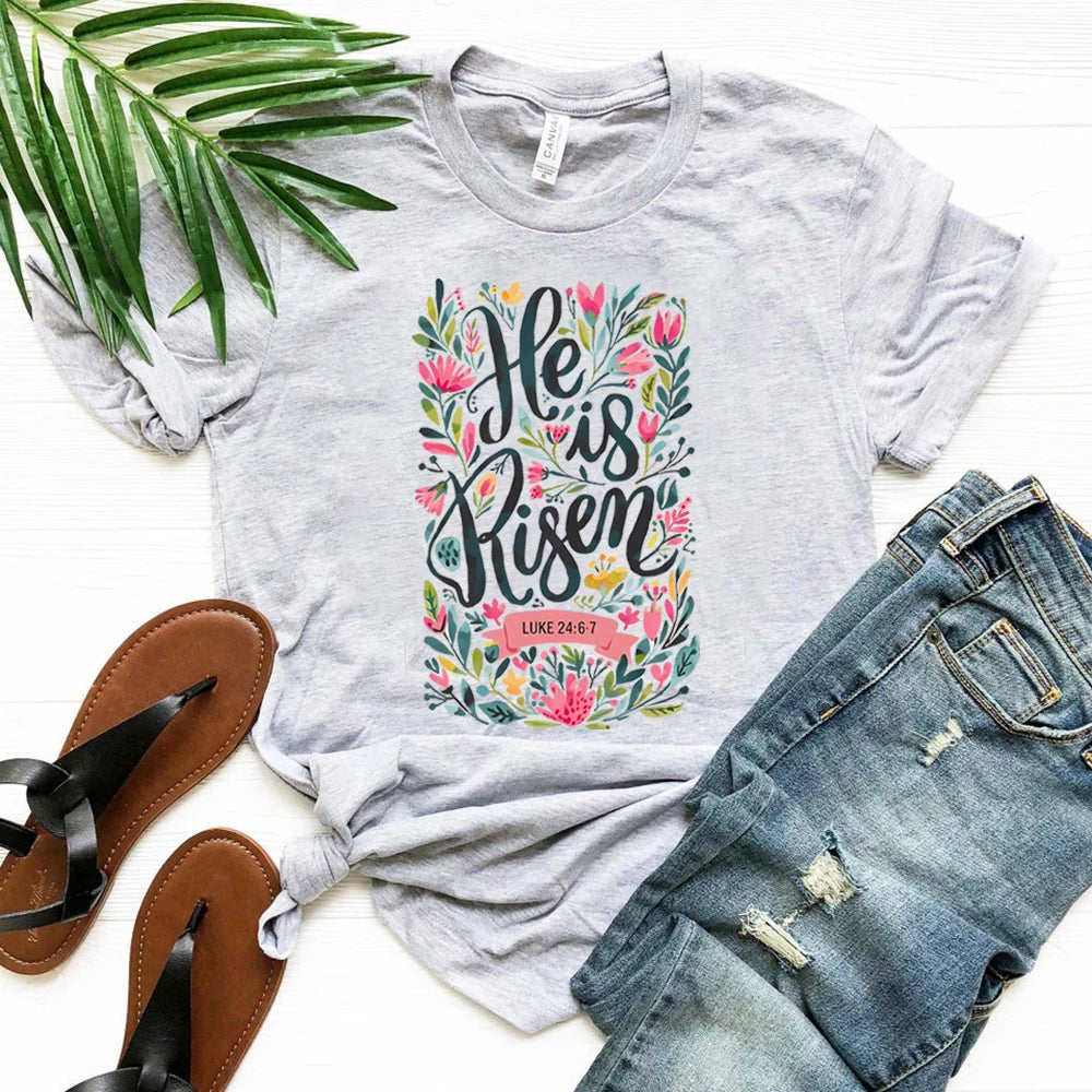 Gray t-shirt with 'He is Risen' design, sandals, and jeans on a white background