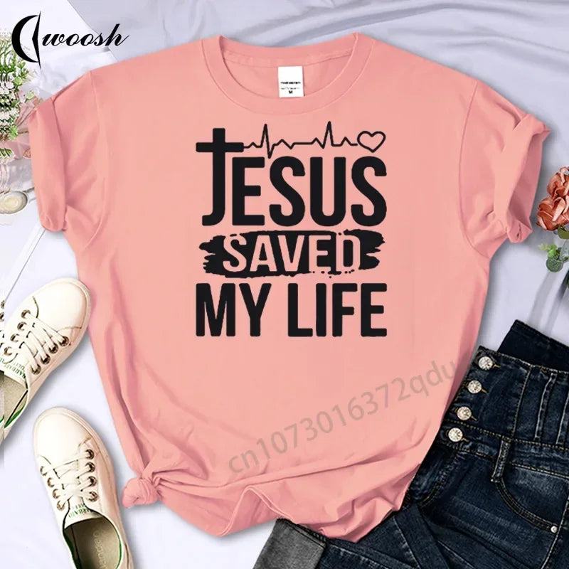 Pink t-shirt with 'Jesus Saved My Life' text on a white background with shoes and jeans.