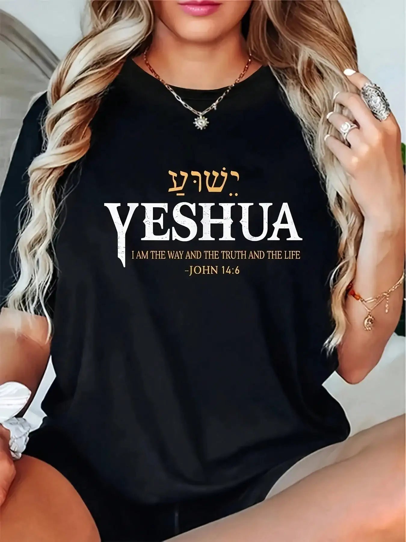 Person wearing a black t-shirt with 'Yeshua' text and John 14:6 quote.