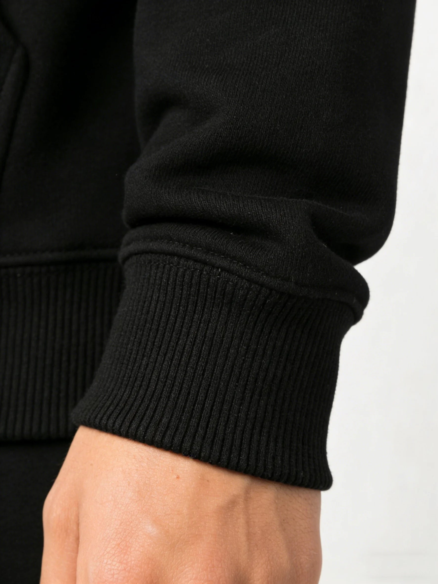 Close-up of a person wearing a black sweater with a white background
