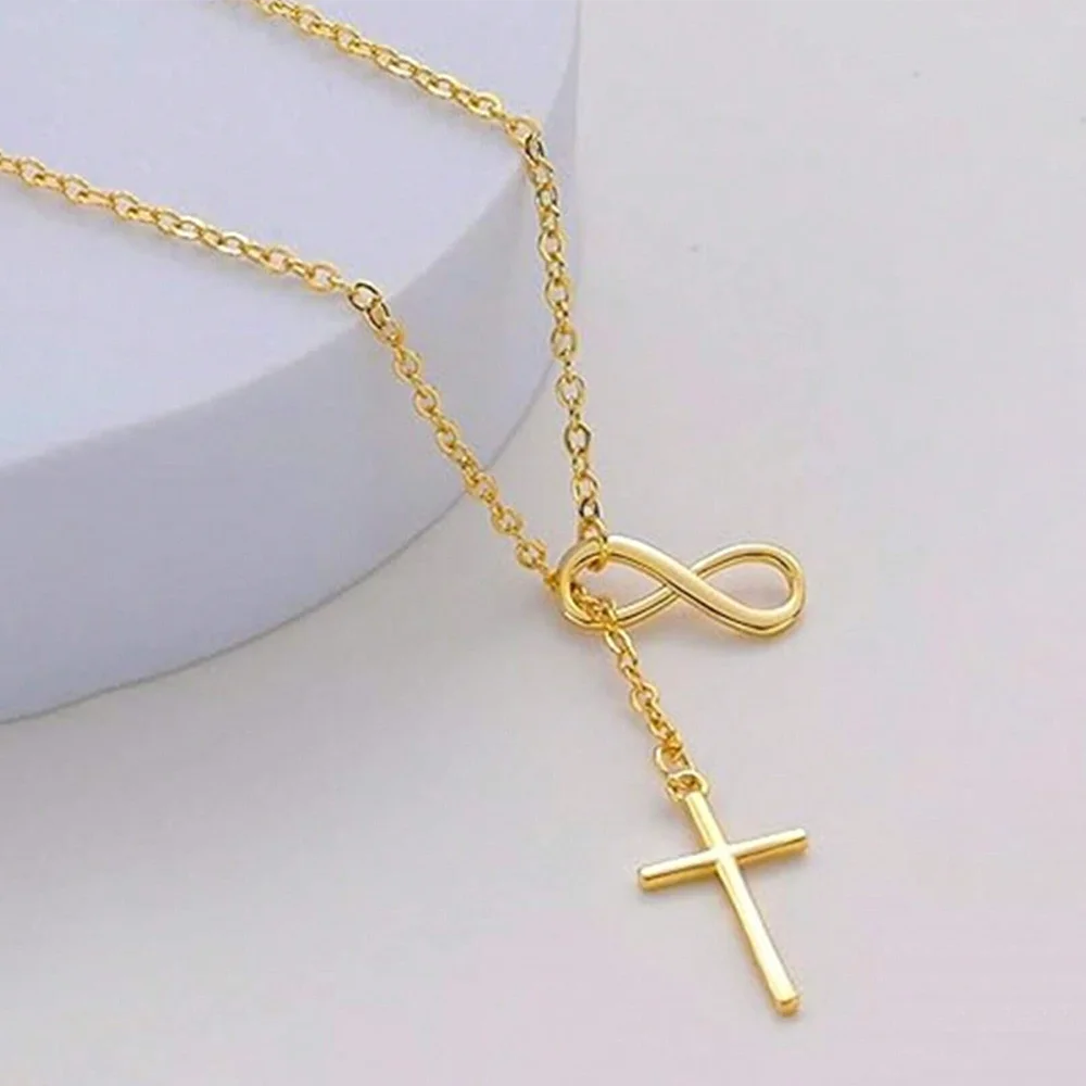 Gold necklace with infinity and cross pendants on a light background