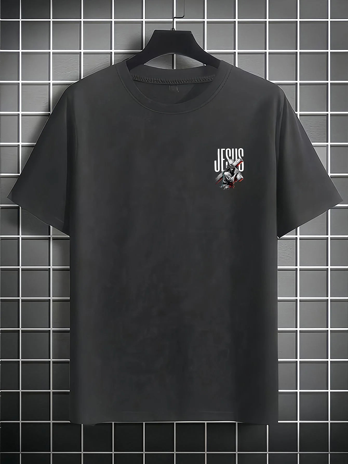 Black t-shirt with 'Jesus' graphic on a hanger against a tiled wall.