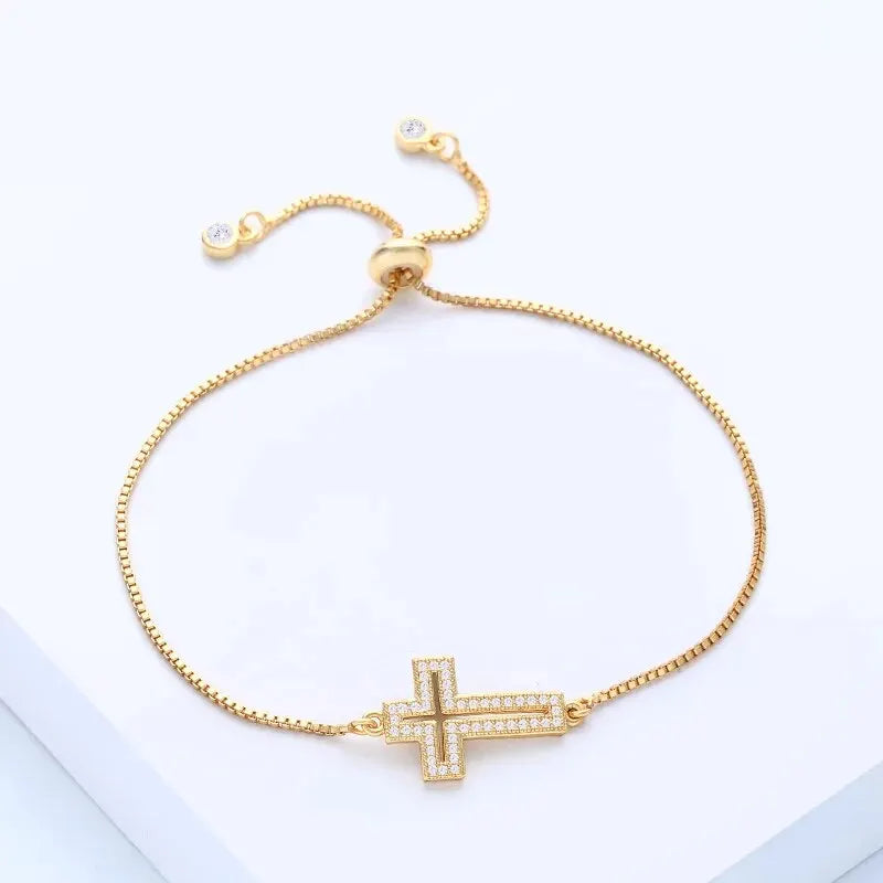 Gold bracelet with a cross charm on a light background