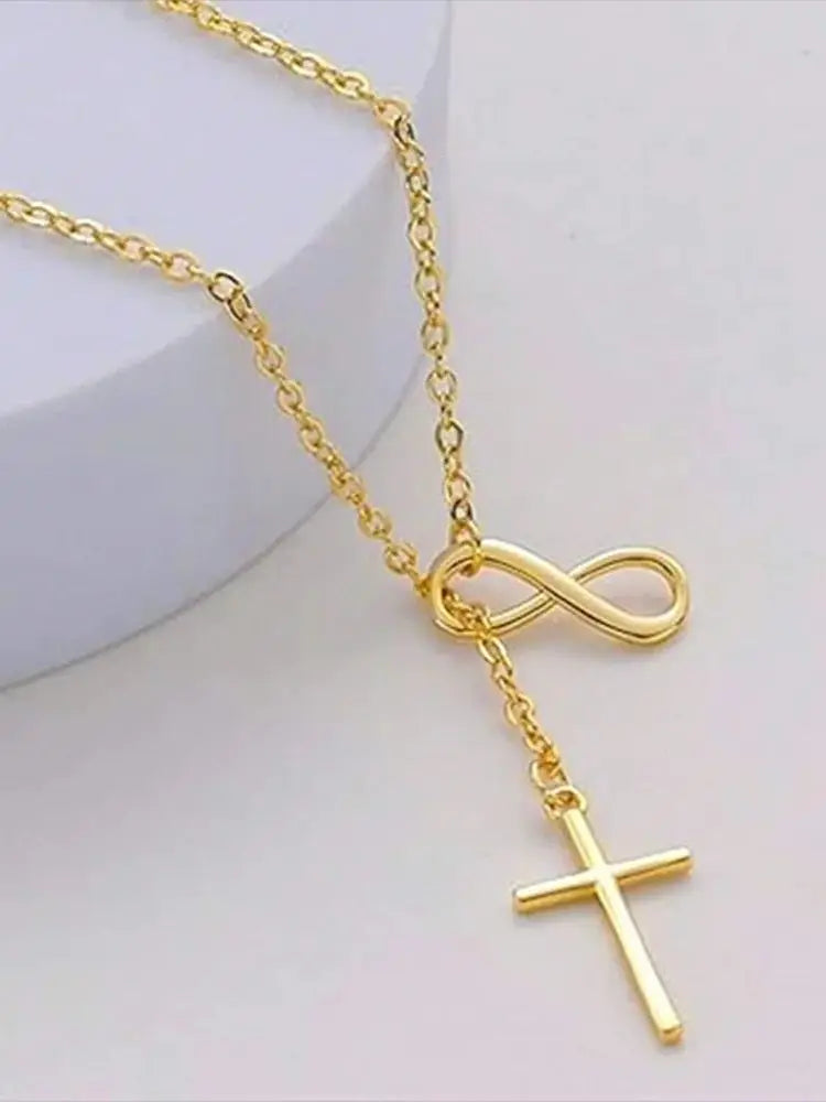 Gold necklace with infinity and cross pendants on a light background