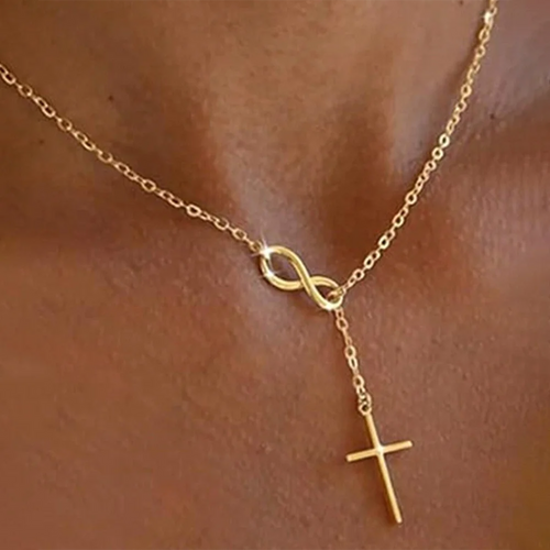 Gold necklace with infinity and cross pendants on a person's neck.