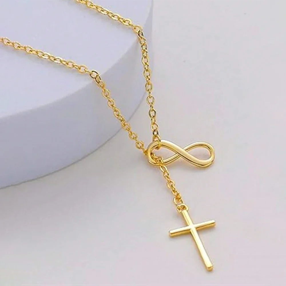 Gold necklace with infinity and cross pendants on a light background