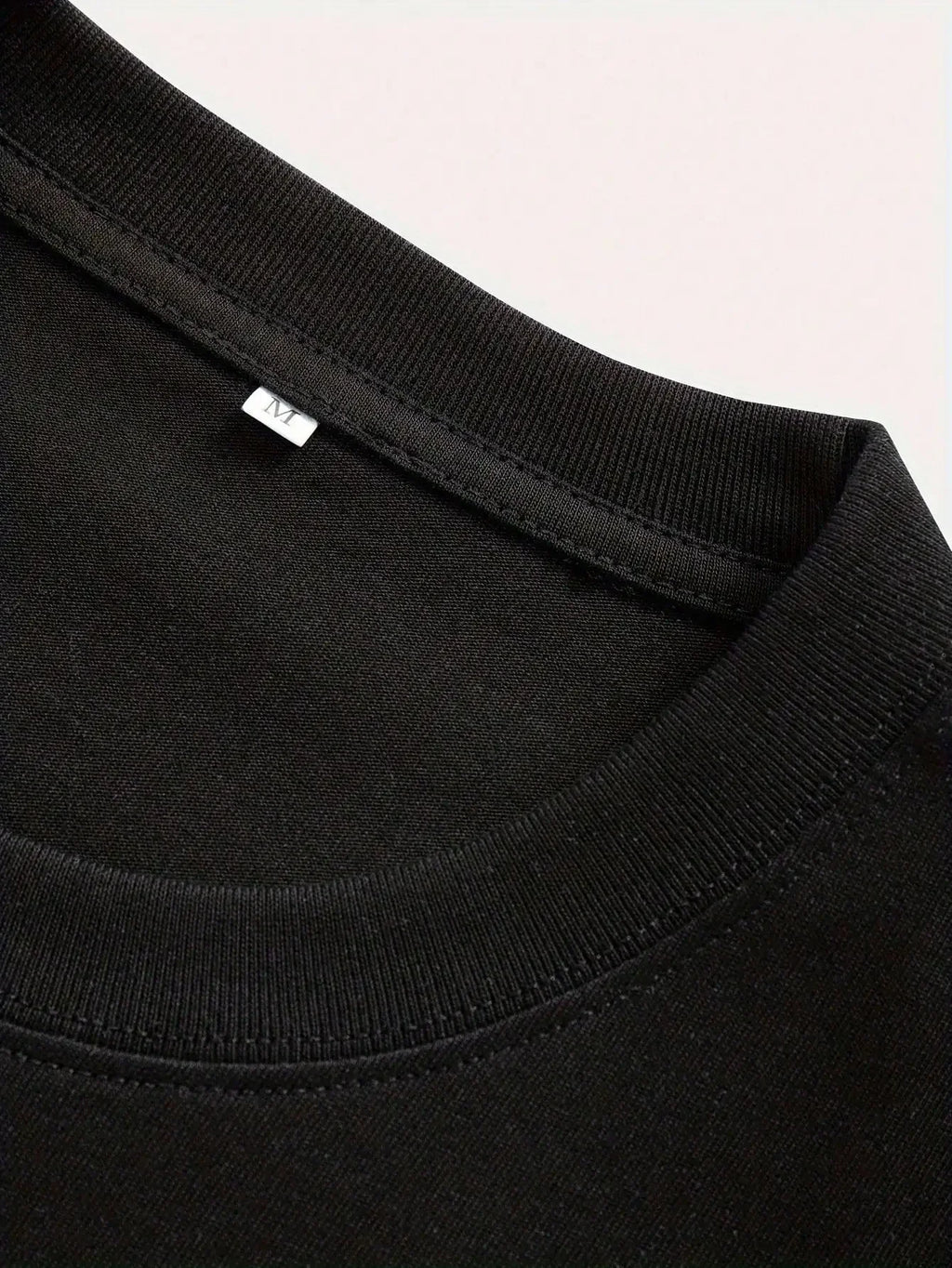 Close-up of a black garment with a brand label on a light pink background