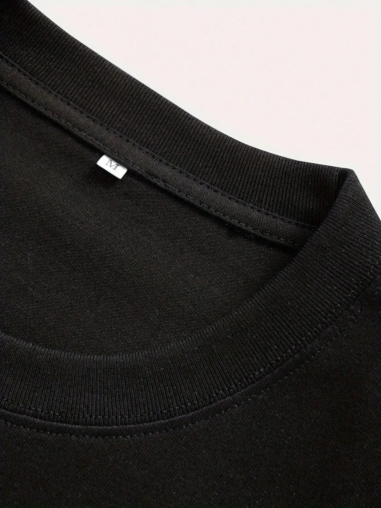 Close-up of a black garment with a brand label on a light pink background